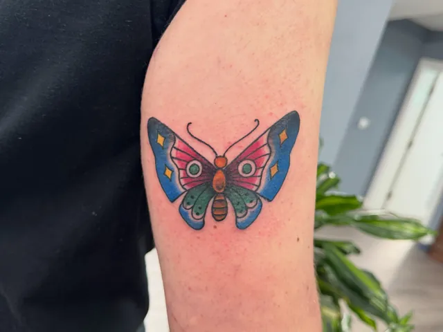 Colour American traditional butterfly tattoo on an arm