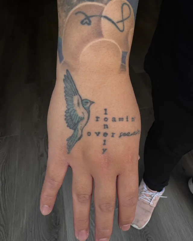 Healed bird and lettering tattoo on a hand, two years on